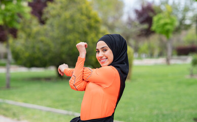 Smiling Arab woman stretching in public park