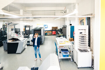 Businesswoman talking on mobile phone in printing press industry