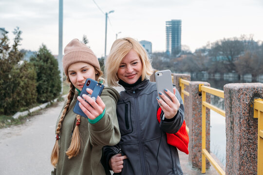 Two fit woman wearing sportswear taking selfie photo while working out in city. Two sports women smiling and doing selfie after running. Friends training outdoors and taking selfie while resting