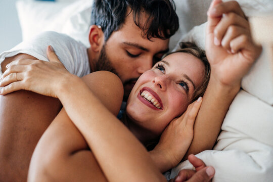 Young romantic couple lying on bed at home