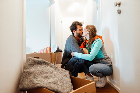 Affectionate couple kissing by box at home