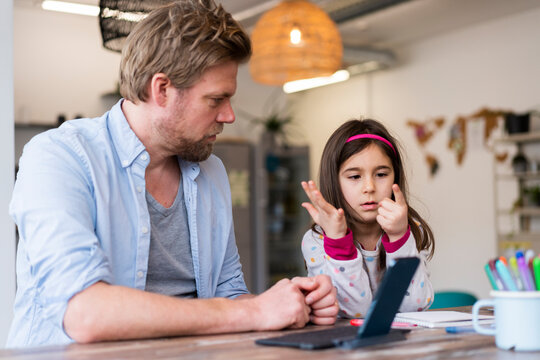 Girl counting fingers while sitting by father at home