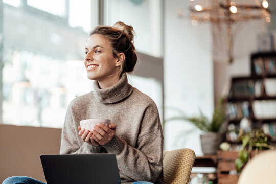 Thoughtful mid adult entrepreneur holding bowl at cafe