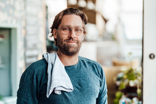 Mature male owner with napkin on shoulder at coffee shop