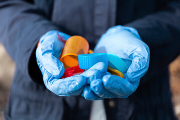 Woman wearing protective glove holding plastic bottle cap