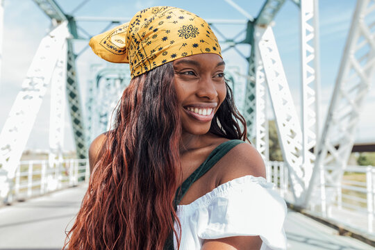 Smiling woman with bandana looking away at bridge