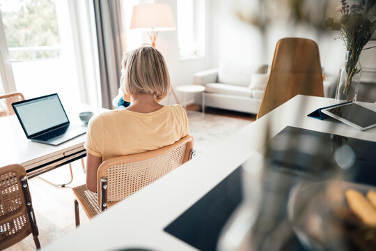 Short haired businesswoman looking at laptop in living room