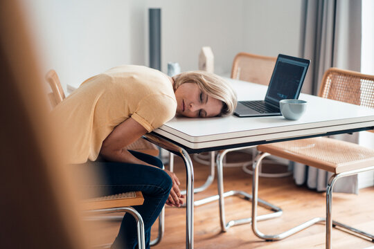 Tired female professional sleeping on table at home