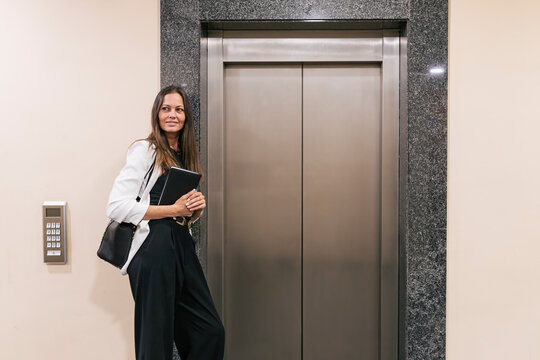 Female entrepreneur holding book while standing by elevator
