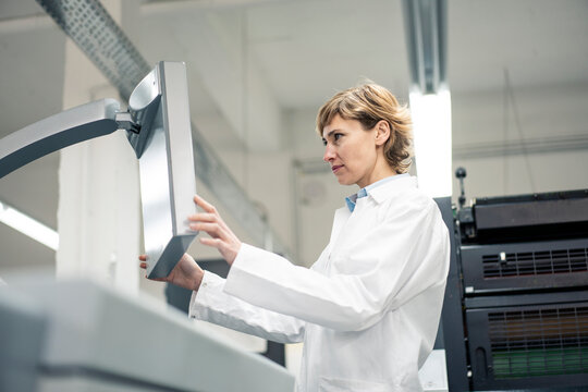 Mature female scientist operating printing machine in laboratory