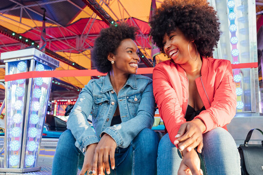 Happy female friends talking with each other while sitting in amusement park
