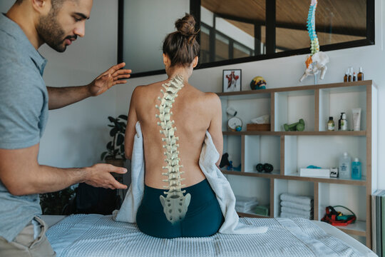 Physiotherapist looking at female patient's bent spine