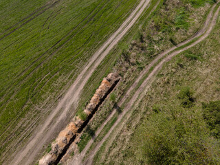 View of a country road in a field from above. Shooting from a height, from a throne, from a bird's eye view. Nature, landscape, road, path.