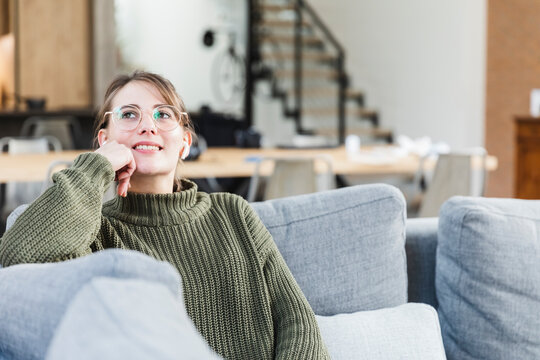 Thoughtful woman sitting on sofa in living room at home