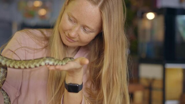 A woman visits a cafe with exotic animals. Cafe where you can contact with animals. She is touching a snake