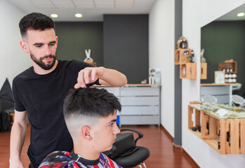 Male barber combing hair of customer while doing hairstyle at salon