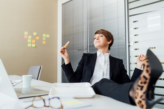 Contemplating businesswoman having lunch while sitting at desk in office