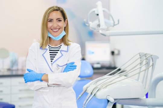 Smiling female dentist with arms crossed standing at medical clinic