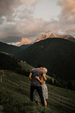 Couple embracing while standing on grass near dolomites moutain ranges in South Tyrol, Italy