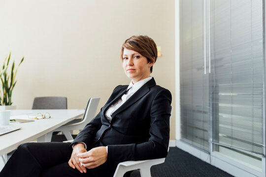 Female entrepreneur with blank expression sitting on chair in office