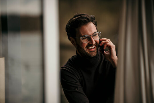 Happy man talking on phone at home office