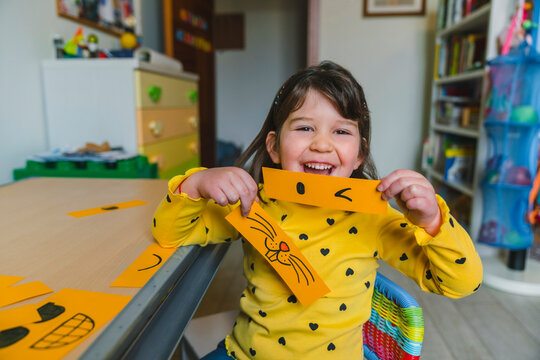 Laughing girl holding emoticons while playing at home