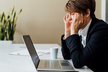 Frustrated female business professional sitting in front of laptop at desk