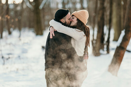 Mid adult boyfriend and girlfriend kissing in forest