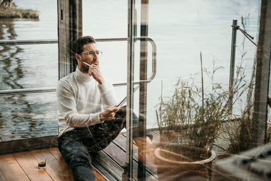 Thoughtful male professional wearing eyeglasses working on houseboat