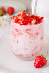 Yogurt with strawberry in glass on wooden table