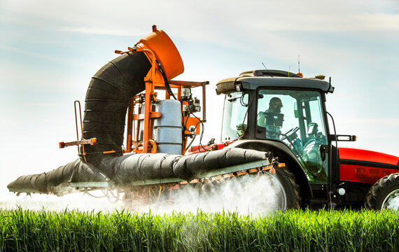 Farmer spraying herbicide on wheat crop while sitting in tractor