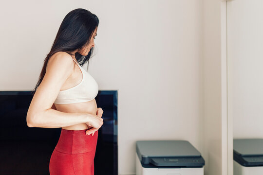 Mature Woman Adjusting Yoga Pants While Standing In Living Room