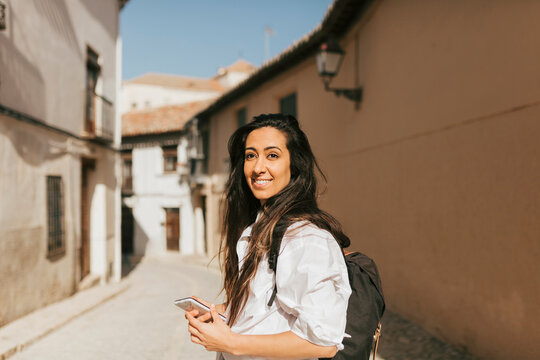 Female Tourist With Backpack And Mobile Phone On Sunny Day