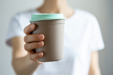 Woman holding disposable cup in front of white background