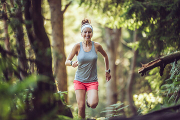 Excited young sportswoman running in forest