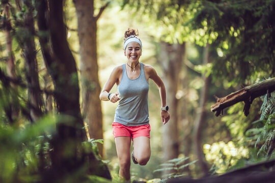 Excited young sportswoman running in forest