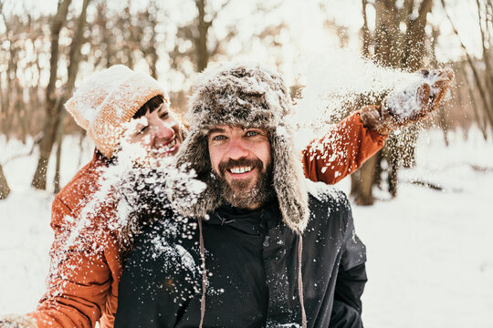 Smiling girlfriend throwing snow on man in forest