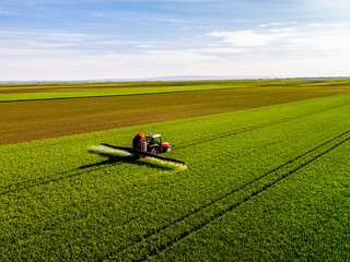 Crop sprayer sprinkling fungicide on wheat field during sunny day