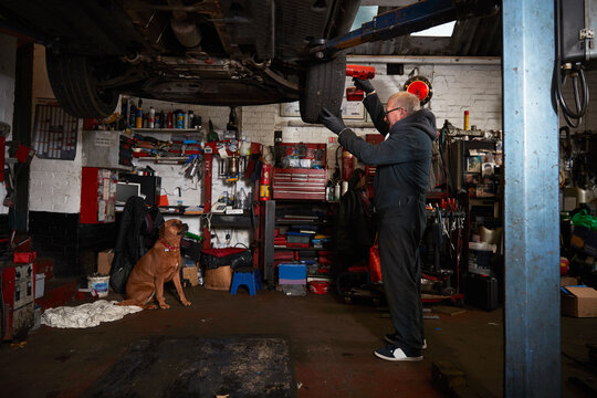 Senior male mechanic replacing tire in garage