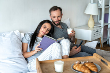 Man and woman having breakfast on bed at home