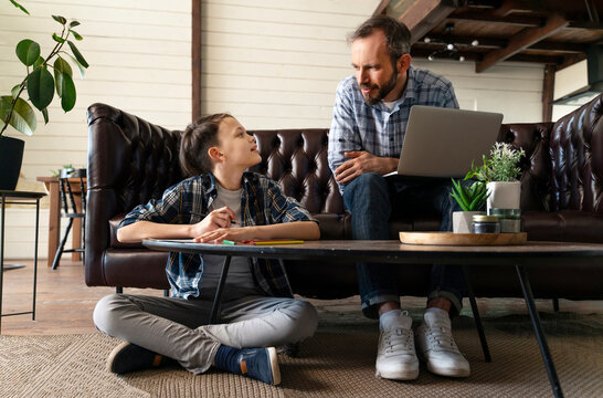 Father with laptop discussing with son while sitting at home