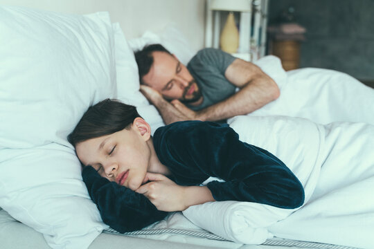Son sleeping with father on bed at home