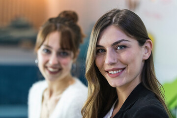 Young smiling businesswoman with colleague in background at office