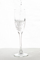 Filling up the champagne glass water  isolated on a white background