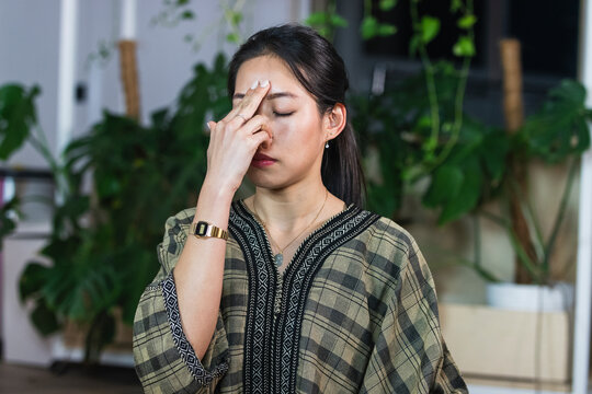Female entrepreneur touching forehead while sitting with eyes closed in creative office