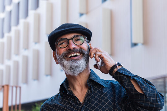 Smiling man looking away while talking on mobile phone in city