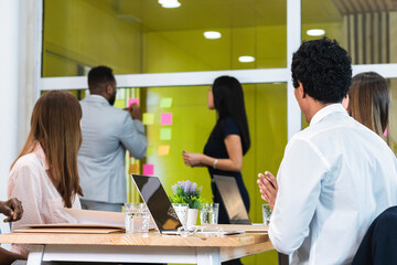Colleagues looking at business people standing by glass wall in meeting