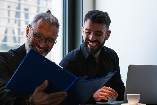 Smiling businessman reading menu by male colleague in coffee shop
