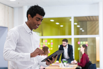 Smiling businessman using digital tablet with colleagues in background at office