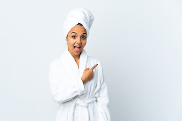 Young woman in bathrobe over isolated white background surprised and pointing side